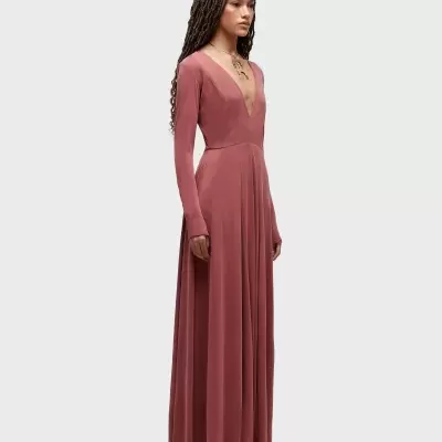 Vestido longo rosa velho de malha com decote em V e mangas compridas num fundo neutro
