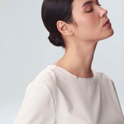 Blusa branca de tecido liso com gola redonda e manga comprida