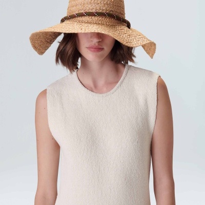 Mulher com vestido creme de malha e chapéu de palha castanho claro