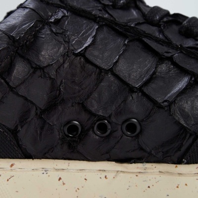 Sapato preto com textura escamosa e sola branca com manchas
