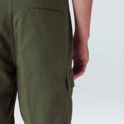 Calções verdes com bolsos em tecido, usados por pessoa com fundo neutro