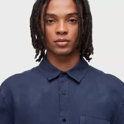 Camisa azul escura de manga comprida com botões pretos e bolso no peito