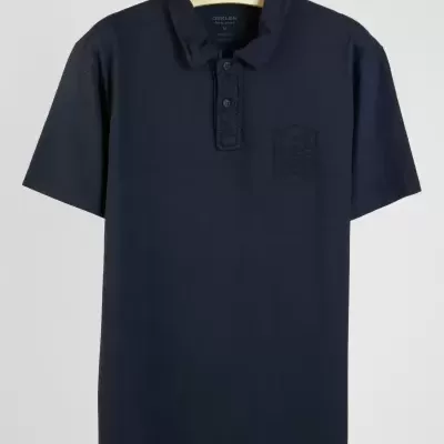 Polo azul escuro de manga curta com gola e três botões pendurado num cabide OSKLEN