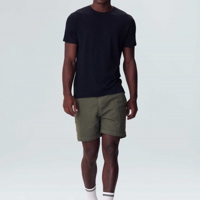 Homem com t-shirt preta, calções verdes, meias brancas com riscas pretas e sapatilhas brancas.