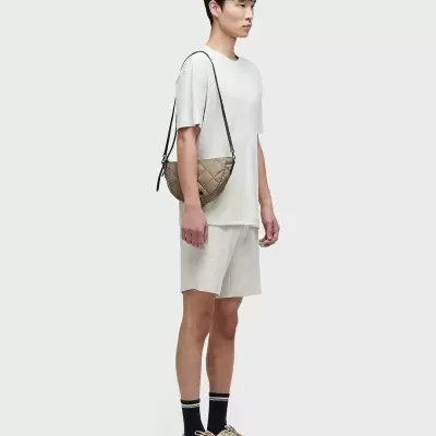 Homem com conjunto casual bege claro e mala acolchoada bege ao ombro