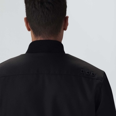 Casaco preto com gola canelada e três botões no ombro, visto de costas