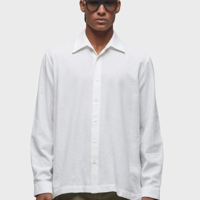 Homem com camisa branca de mangas compridas e calças verdes