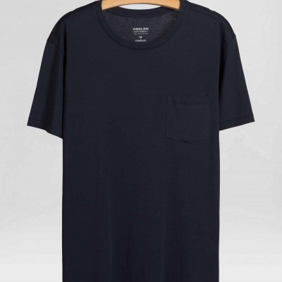 T-shirt preta com bolso pendurada em cabide de madeira em fundo cinza claro