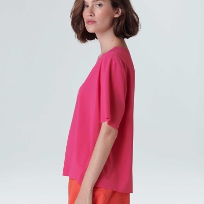 Mulher de perfil com t-shirt rosa e calções laranja