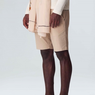 Homem a usar calções e ténis bege com lenço bordado