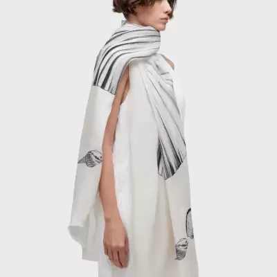 Lenço branco com conchas em tons de cinza e preto usado por modelo
