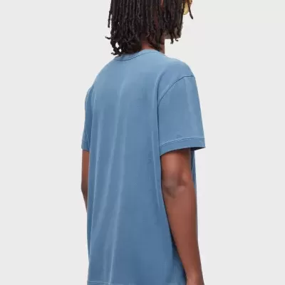 T-shirt masculina azul de algodão vista de costas com calções azuis e etiqueta OSKLEN