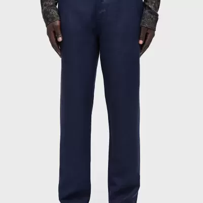 Calças masculinas azul escuro, usadas com camisa escura estampada e sandálias cinzentas