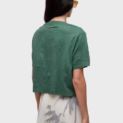 Mulher de costas com t-shirt verde e calções bege com padrão de folhas