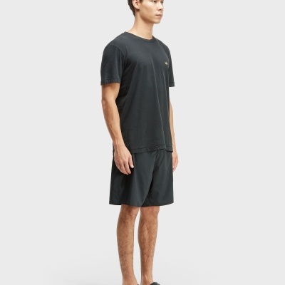 Homem com t-shirt preta, calções pretos e chinelos pretos