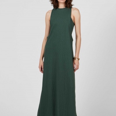 Vestido comprido verde escuro sem mangas usado por mulher em fundo cinzento.