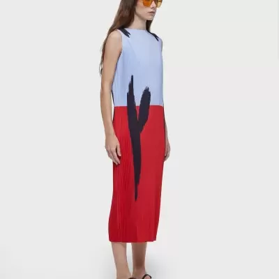 Mulher a usar vestido midi bicolor azul e vermelho com desenho preto, sandálias pretas e óculos de sol amarelos