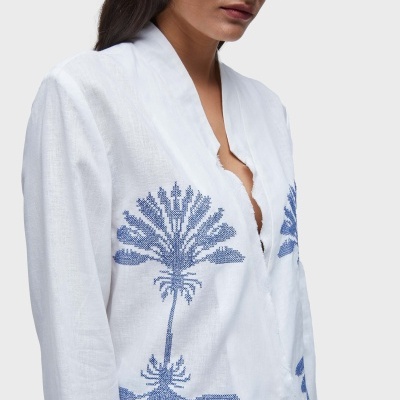 Blusa branca com bordado azul e botões forrados vista em modelo com óculos escuros