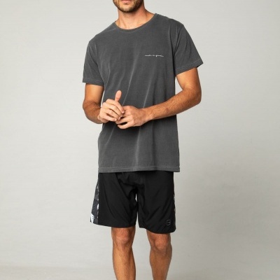 Homem com t-shirt cinzenta escura e calções pretos em fundo cinzento claro