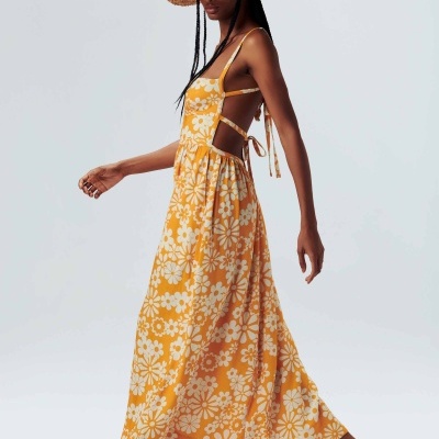 Vestido longo amarelo com flores brancas, chapéu de palha e sandálias bege