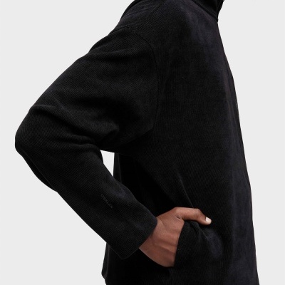 Jersey preto de malha com gola subida e fecho, detalhe da manga com marca OSKLEN