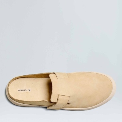 Sapato mocassim slip-on bege em camurça com sola branca numa superfície cinza claro