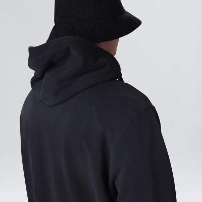 Pessoa vista de costas com chapéu bucket preto e casaco preto com capuz