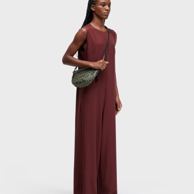 Mulher com vestido vinho longuíssimo e bolsa verde pequena com padrão de escamas.