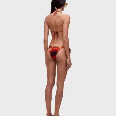 Biquíni colorido feminino visto de costas com sandálias pretas e óculos amarelos