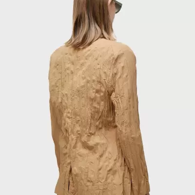 Blazer castanho claro com textura vincada usado por mulher vista de costas