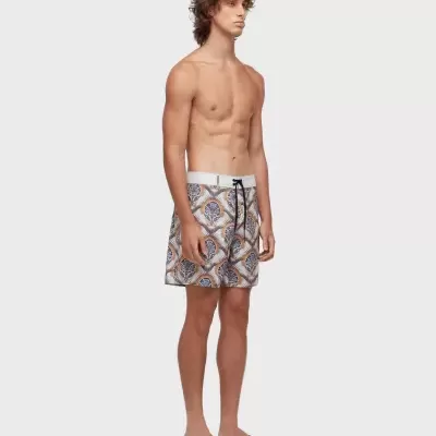 Calções de banho masculinos com padrão de folhas e círculo em azul e castanho, cintura branca e chinelos castanhos.