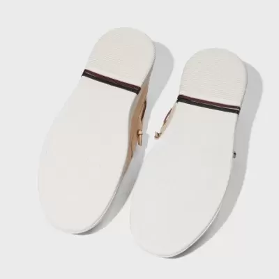 Solas brancas de sapatos com faixa preta e vermelha, sobre fundo branco