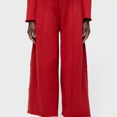 Calças largas vermelhas com bainha desfiada e tênis brancos com sola vermelha