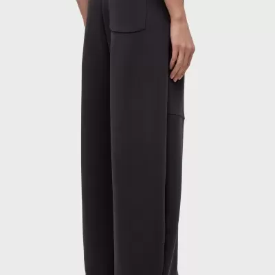 Calças largas pretas com bolso nas costas e ténis brancos.