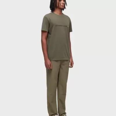 Homem com t-shirt verde com texto preto e calças verde-oliva com sapatilhas brancas