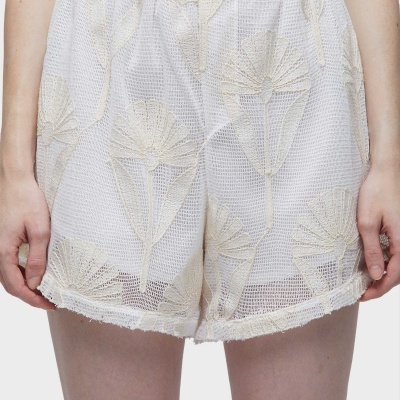 Calções brancos em rede com padrão de folhas bordadas em bege