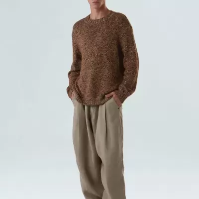 Homem com camisola castanha e calças largas bege