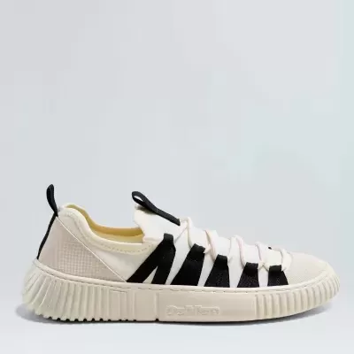 Ténis branco com detalhes pretos e sola bege em fundo claro