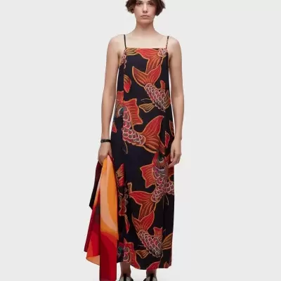 Vestido longo com padrão de peixes koi em tons quentes e modelo segurando tecido degradê