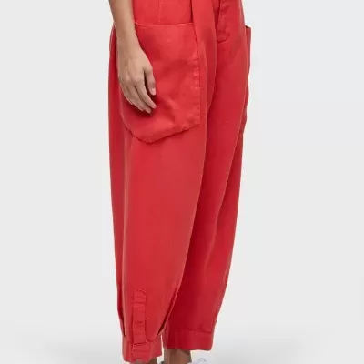 Calças vermelhas com bolsos grandes e cinto, usadas com ténis brancos.