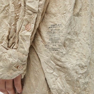 Camisa bege enrugada com etiqueta de instruções OSKLEN