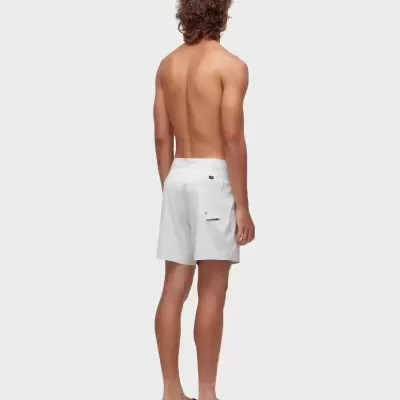 Homem de costas com calções de banho brancos e chinelos pretos