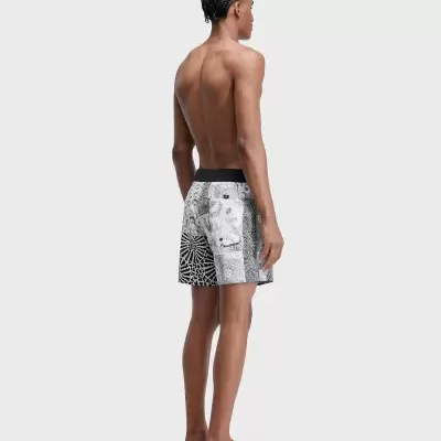 Homem visto de costas a usar calções de banho preto e branco com padrão geométrico e floral.