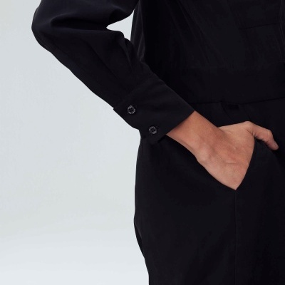 Manga comprida preta com punho abotoado e mão no bolso lateral.