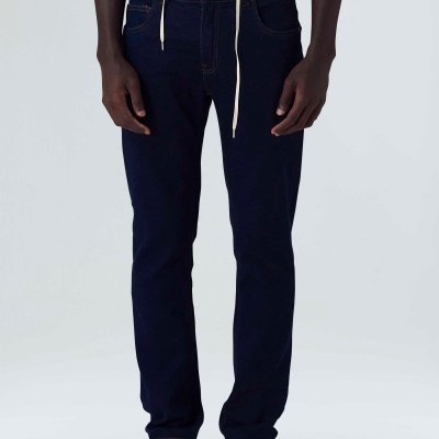 Calças de ganga azul escuro com cinto branco e ténis bege em fundo branco