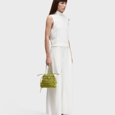 Mulher com roupa branca e mala verde trançada