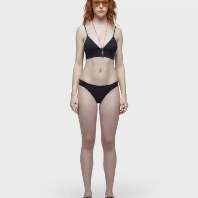 Conjunto lingerie preto com sandálias e óculos de sol âmbar em fundo branco.