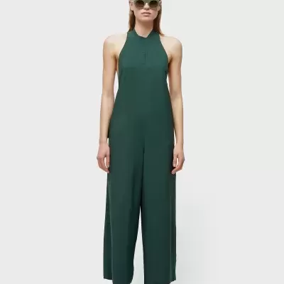 Macacão verde escuro com decote halter, pernas largas, usado com ténis e óculos de sol