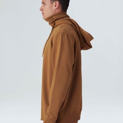 Homem de perfil com camisola de capuz castanha e calças castanhas