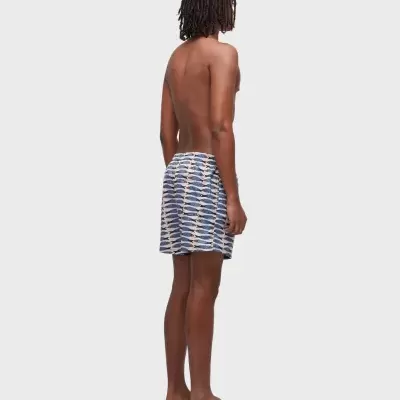 Homem de pé com calções de banho estampados e chinelos